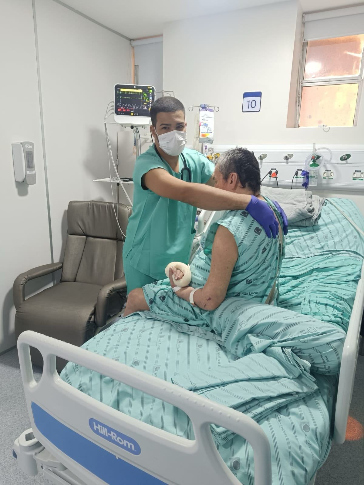Técnico da Cuidare em scrubs do Hospital São Lucas cuidando de paciente no leito